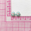 A pair of small, light green resin penguin figurines placed on a pink ruler.
