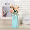 A light blue plastic vase holds a bouquet of pink and peach roses with natural twine wrapping.