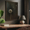 A dark canvas art piece featuring a dandelion seed head against a dark background displayed on a wooden table.