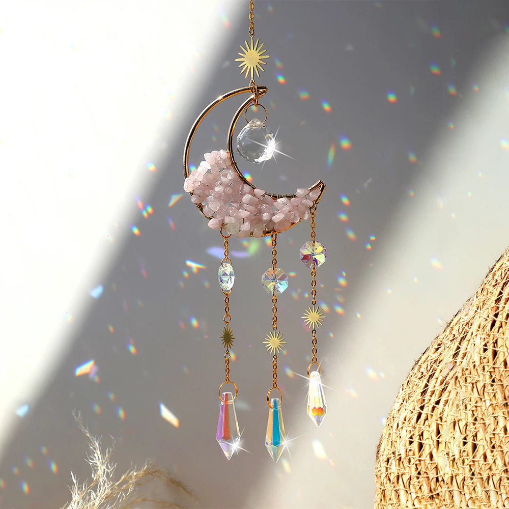 A hanging moon-shaped crystal suncatcher with pink crystals and rainbow prisms.