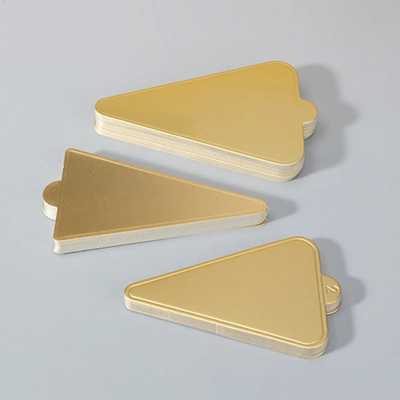 A stack of metallic gold dessert cake boards with silver edges, shown from a side angle.