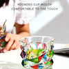 A faceted crystal whiskey glass with colorful geometric cuts is shown on a white surface.