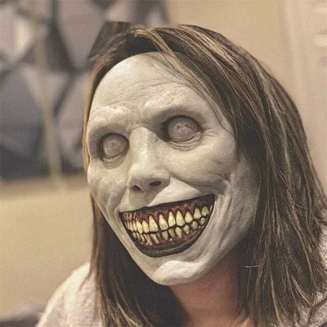 A woman wearing a realistic, pale gray animal mask with exaggerated teeth and facial features.