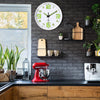Horloge murale plastique lumineuse moderne avec cadran blanc et aiguilles vertes, suspendue sur un mur de briques gris foncé 