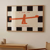 A framed wall art print featuring an orange silhouette of a standing figure against a black and white checkered background wi