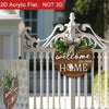 A wooden welcome sign with a wreath and bow hangs from a white decorative iron fence.
