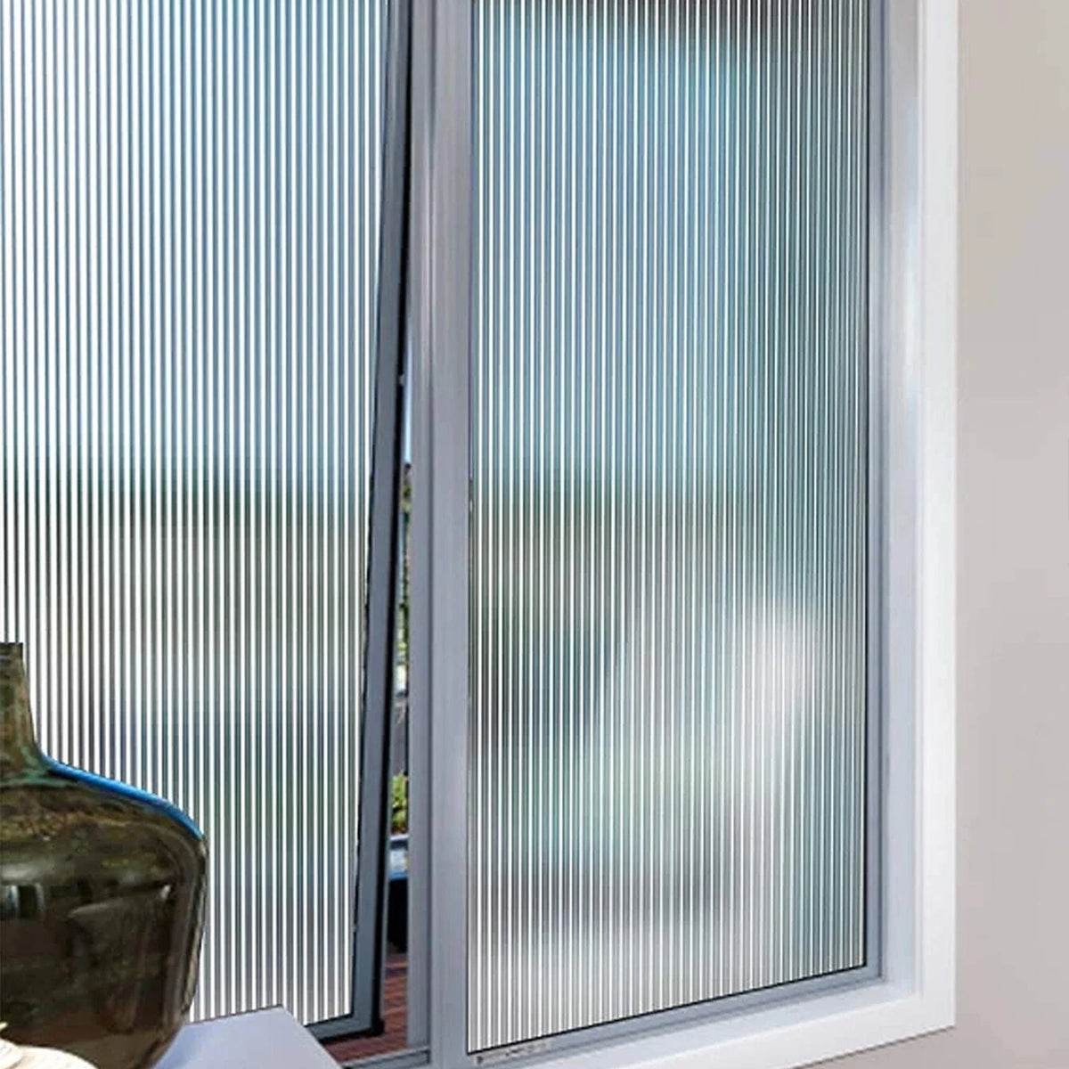 A close-up view of a vertical frosted window privacy film installed in a window frame.