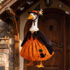 A decorative Halloween lawn goose costume featuring an orange pumpkin outfit, black cape, and witch hat.