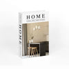 A white book titled HOME with a black spine and text on the cover, displayed against a light background.