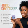 A smiling woman holds a purple hand sanitizer spray bottle against her skin.