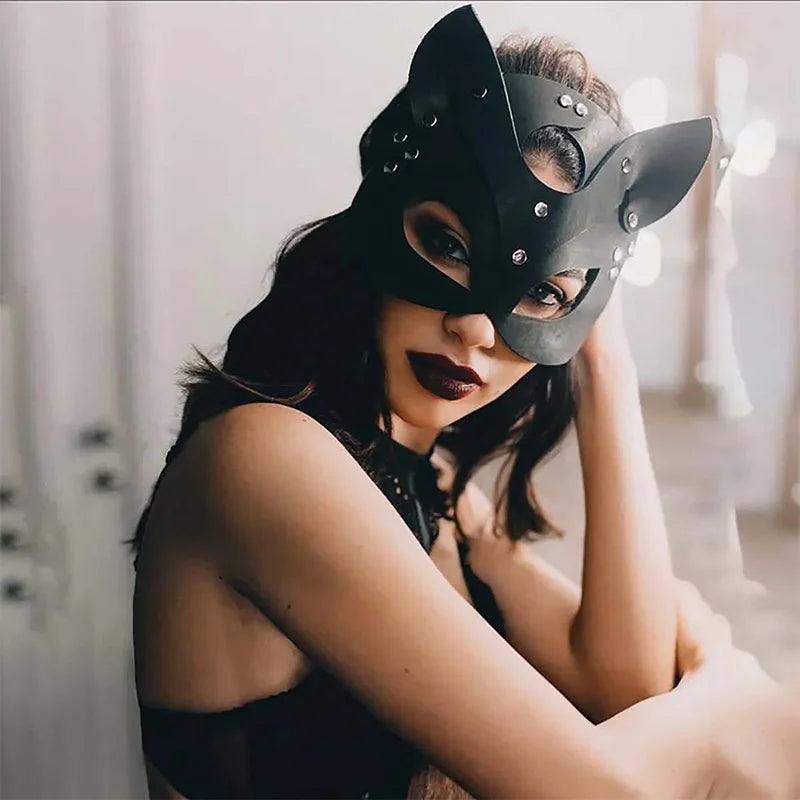 A woman wearing an elegant black fox masquerade mask with adjustable straps, looking directly at the camera.