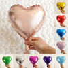 A collection of heart-shaped foil balloons in various colors including pink, red, blue, and green, held by a hand.