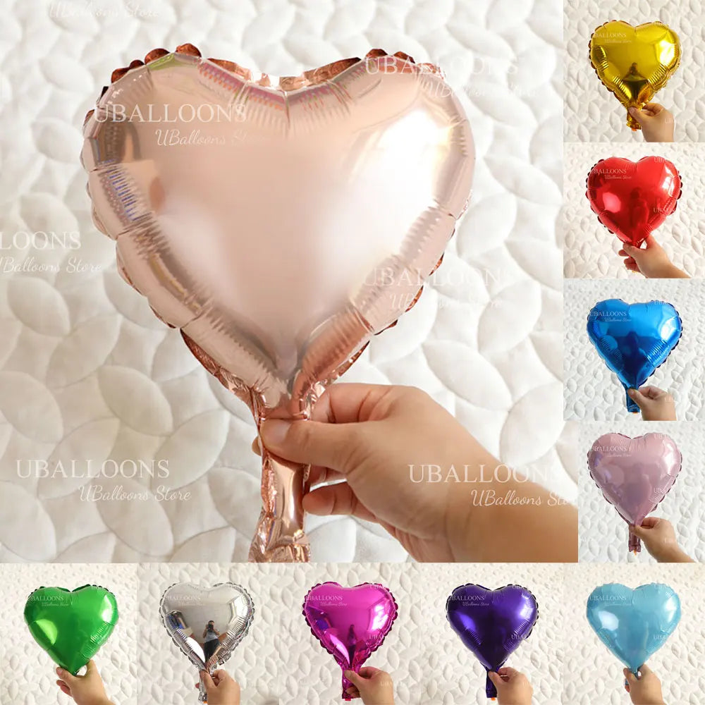 A collection of heart-shaped foil balloons in various colors including pink, red, blue, and green, held by a hand.