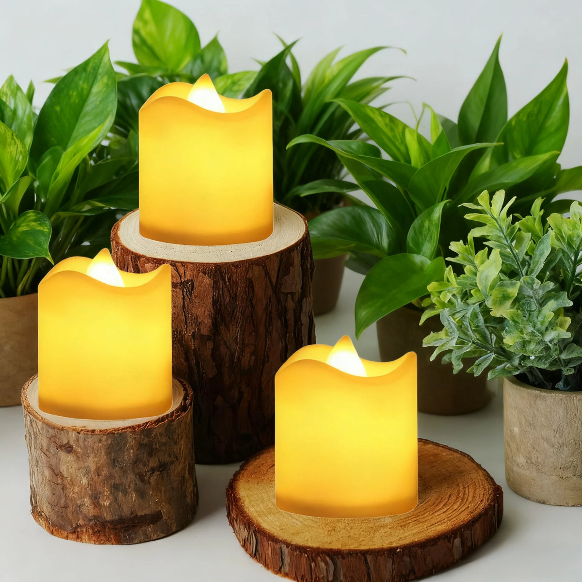 A set of glowing yellow LED votive tea lights in natural wood holders surrounded by green foliage.