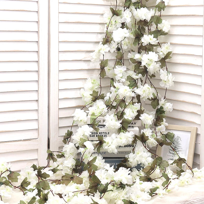 An artificial sakura flower garland draped across a white wooden window frame.
