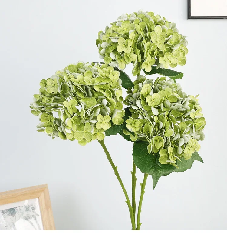 A cluster of artificial light green hydrangea flowers on a green stem against a white background.