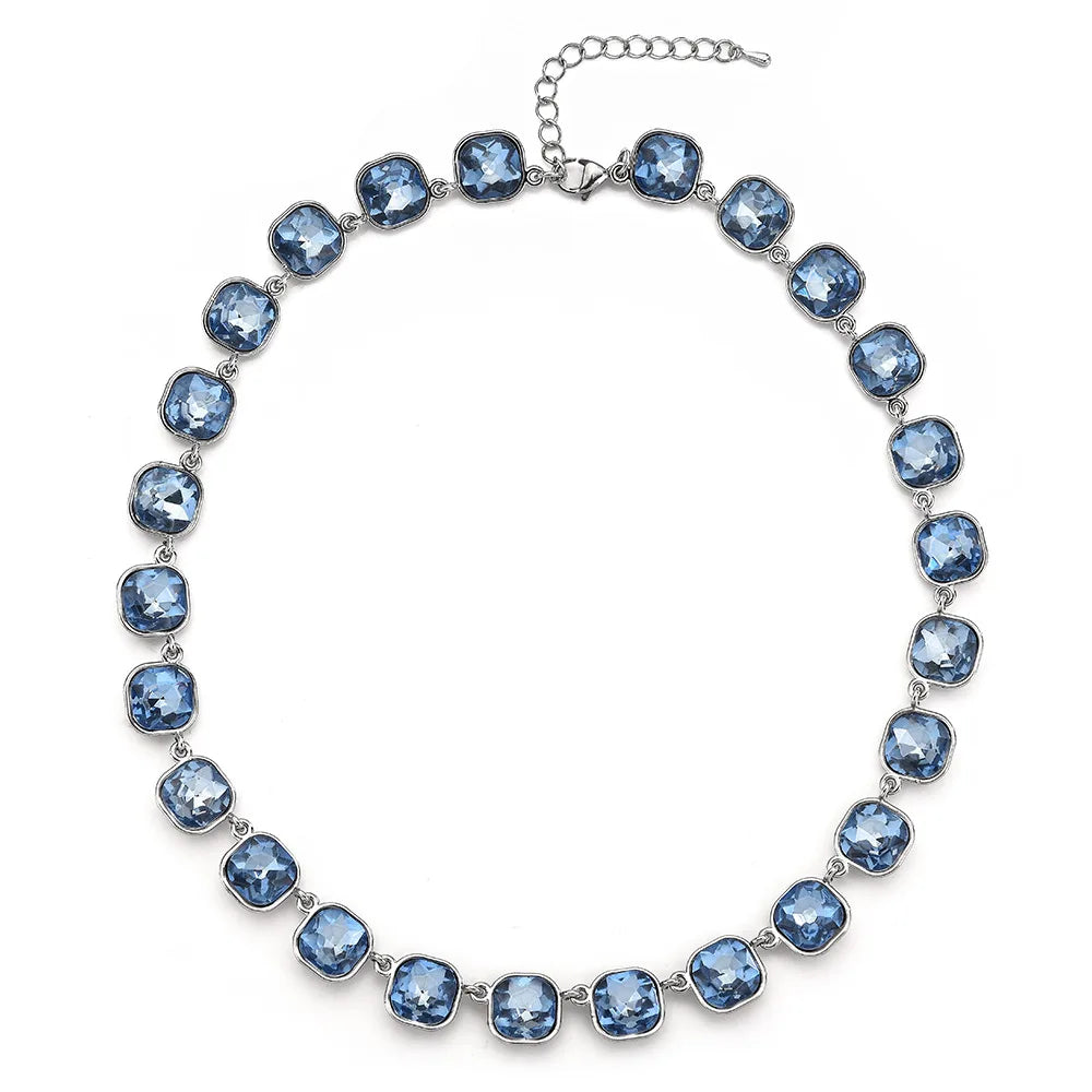 A silver-toned crystal pendant necklace featuring round blue gemstones connected by a chain.