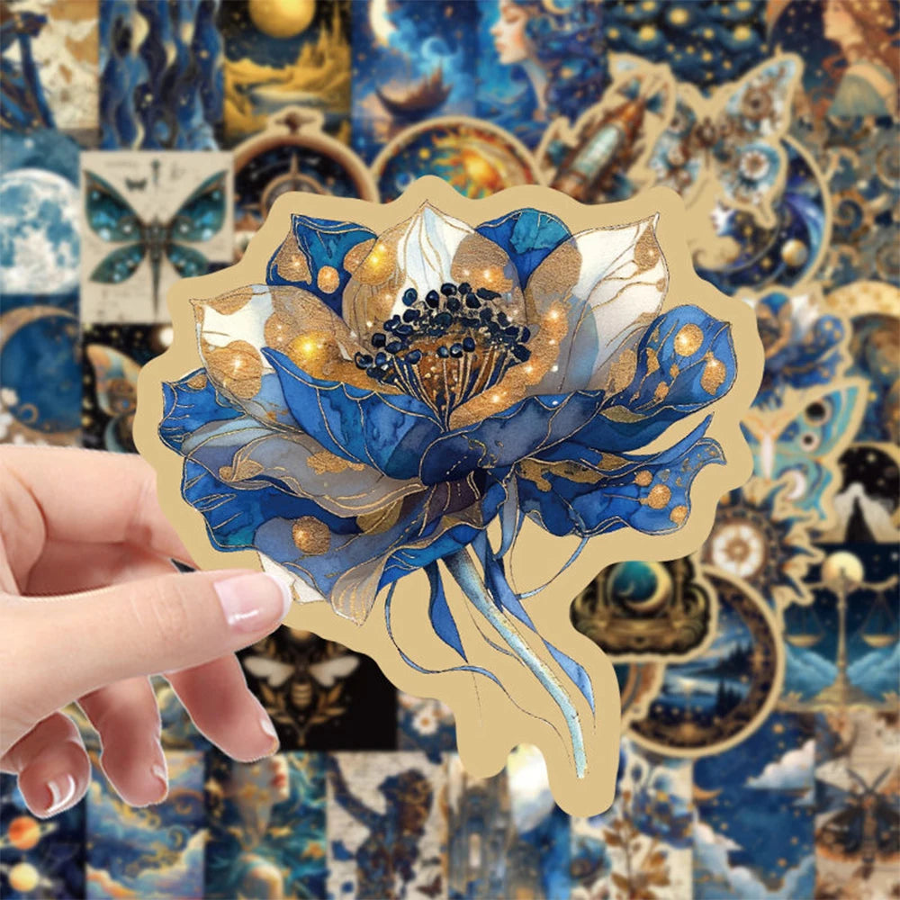 A hand holds a sticker pack featuring blue and gold floral designs on a textured background.