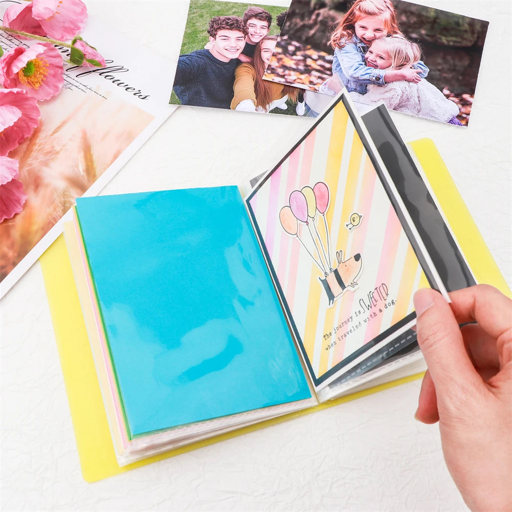 A hand holds an open clear storage album with colorful pages and photos, showing a journey with a dog.