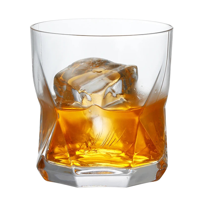 A heavy base tumbler glass filled with amber whiskey and large ice cubes.