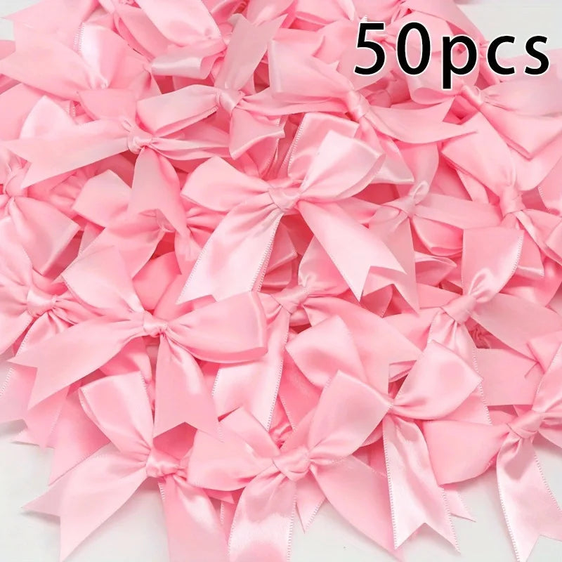 A pile of 50 pink satin ribbon bows for gift wrapping and decor.