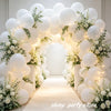 An archway decorated with white latex balloons and greenery for a party backdrop.