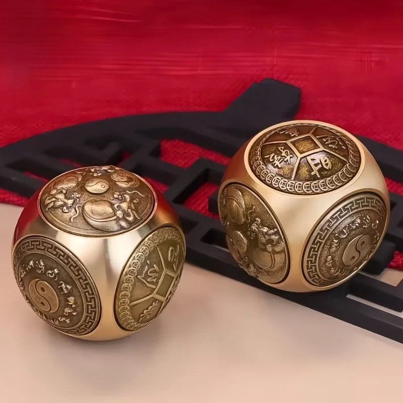 A set of gold-toned Chinese lucky coin spinners or fidget toys resting on a dark surface with a red cloth background.