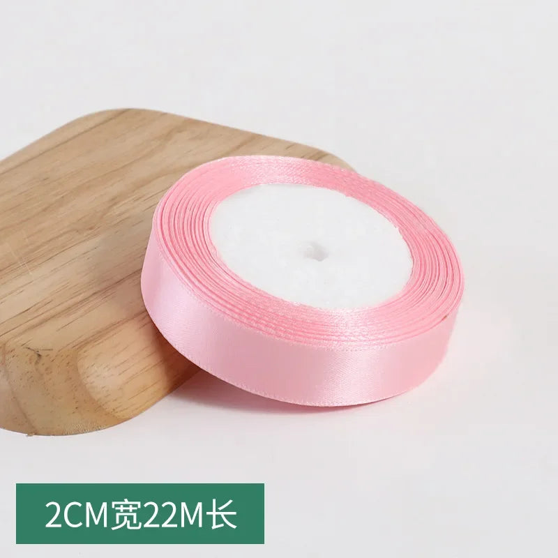 Pink silk satin ribbon roll with white padding and a measurement label