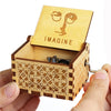 A carved wooden music box with a lid displaying the word IMAGINE, held in a person's hand.