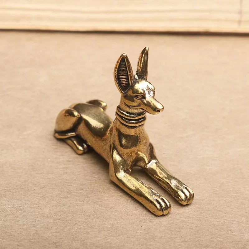 A vintage brass statue of a Pharaoh Hound dog, inspired by Egyptian motifs, resting on a neutral background.