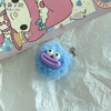 A fluffy blue plush charm shaped like a sausage with a purple mouth and attached to a small silver keyring.