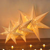 A decorative light fixture shaped like an elegant hollow star, illuminating a wooden surface.
