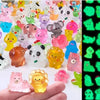 A collection of colorful luminous resin animal figurines, including cats, bears, and other creatures, displayed on a hand.
