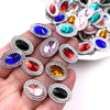 A hand holds a collection of colorful gemstone flatback rhinestones for crafting.