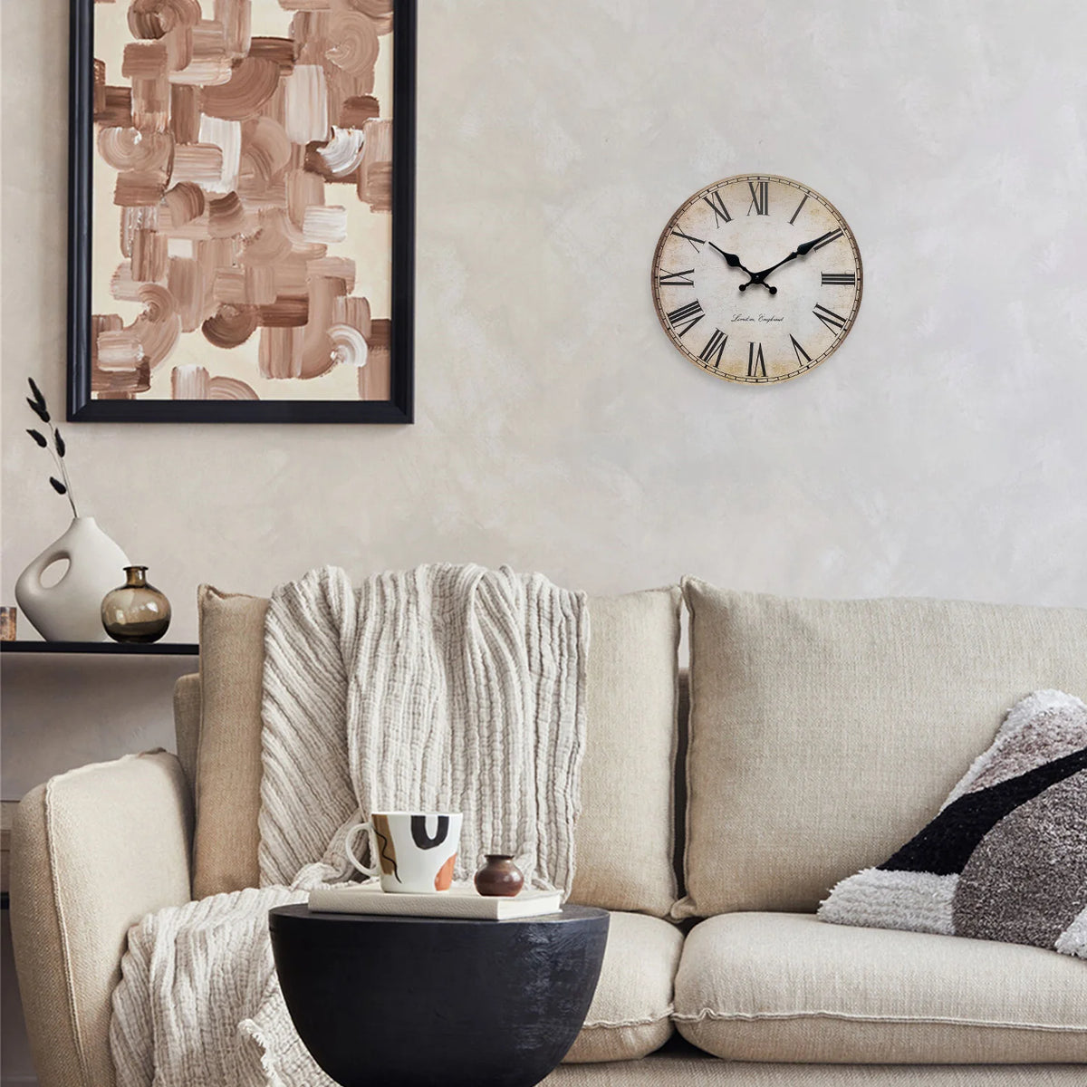 A round wooden wall clock with Roman numerals hangs on a light-colored wall above a beige sofa.
