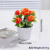 An artificial orange and red rose bonsai tree decoration in a white pot.