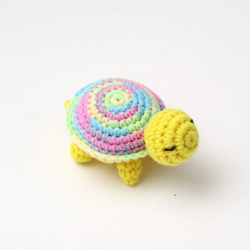 Handmade crocheted turtle plush with a colorful, striped shell and yellow body.