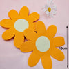Orange felt daisy flower with a light green center and a white flower in the background