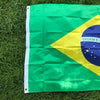 A large green and yellow Brazil flag is displayed on green grass.