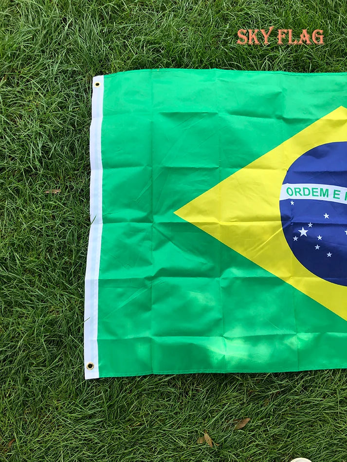 A large green and yellow Brazil flag is displayed on green grass.