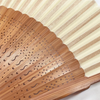 A close-up of an elegant bamboo folding fan with a classic design showing fine perforations and natural wood grain.