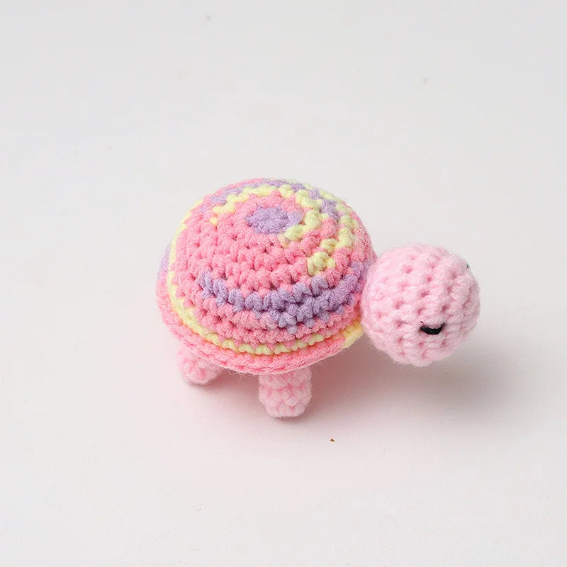 Handmade crocheted turtle plush toy with pink and purple stripes.