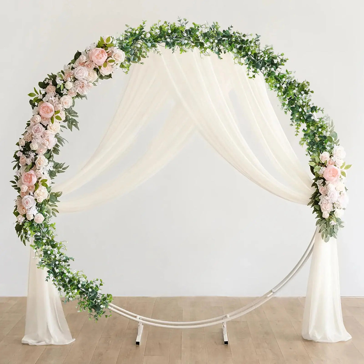 A white draped archway decorated with a lush garland of pink roses and green eucalyptus vines.