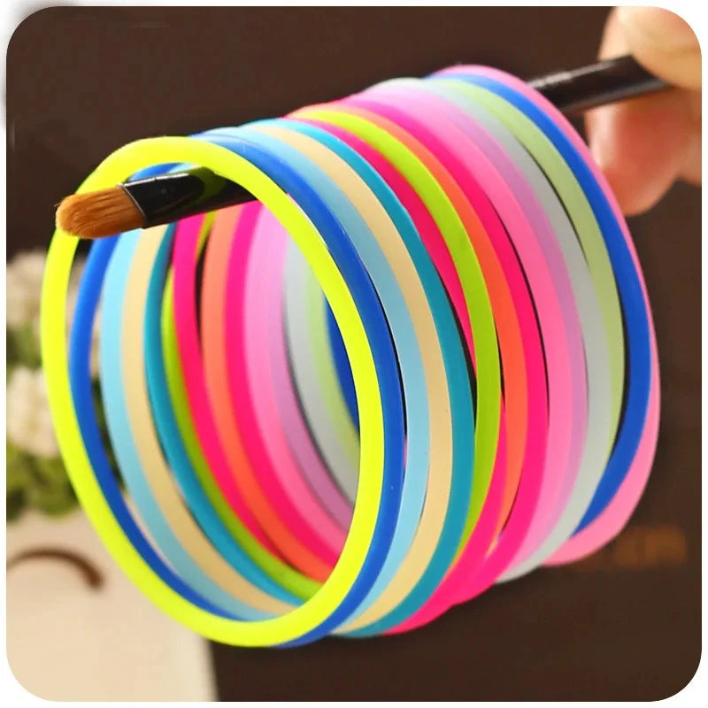 A hand is holding a stack of ten glow-in-the-dark silicone bracelets in various bright colors, viewed from above.