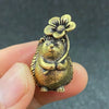 A small brass figurine of a hedgehog with a leaf and flower detail, held in a hand.