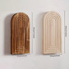 Un par de jarrones de madera arqueados con ranuras verticales, mostrando diferentes tonos y tamaños de madera.