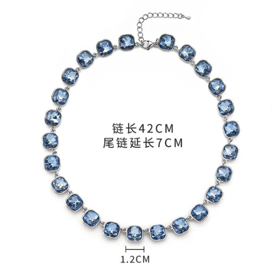 A silver crystal pendant necklace featuring round blue stones and a lobster claw clasp.