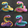 Four colorful 3D printed rotatable snake art models in yellow, pink, purple, and green.