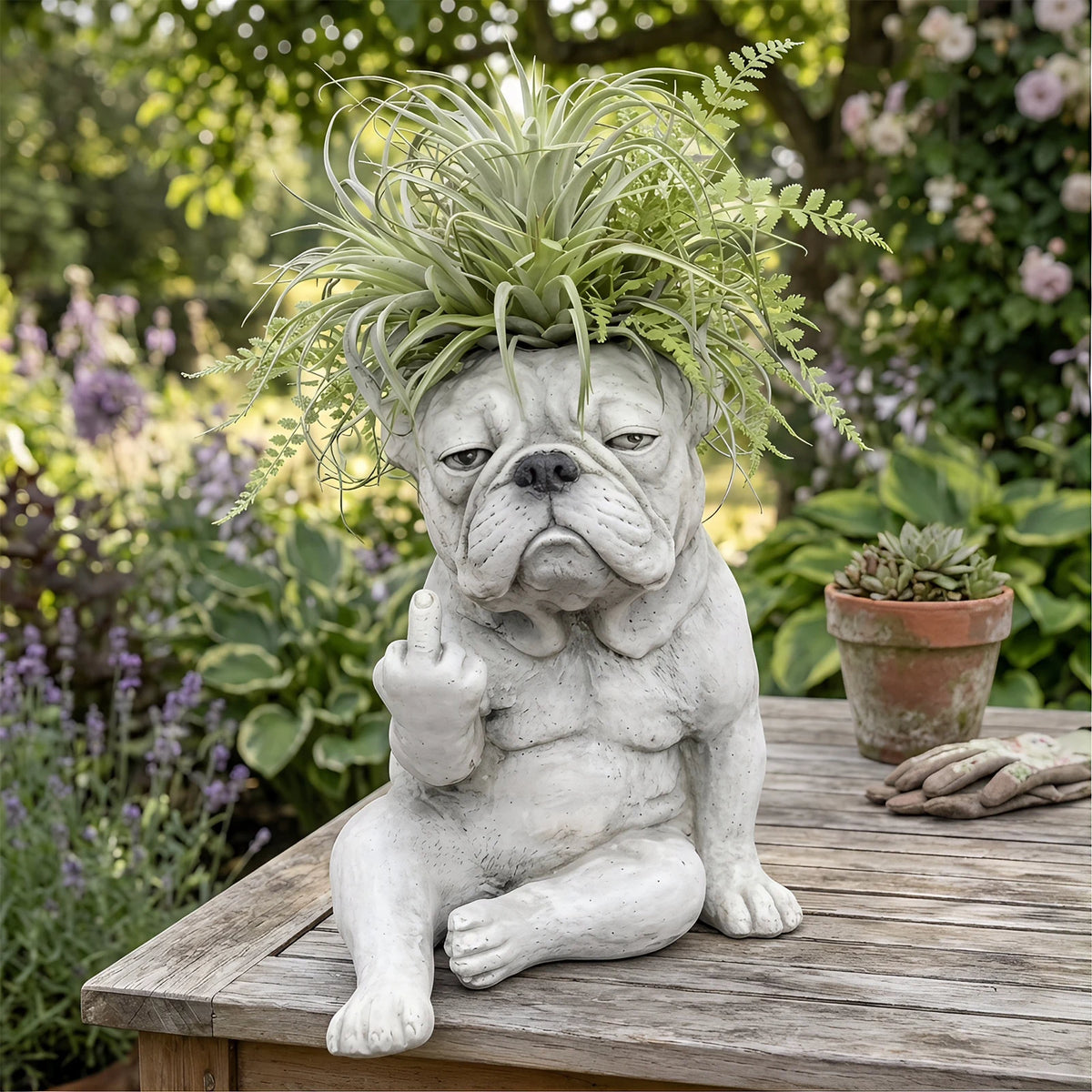 Sculpture réaliste d'une tête de bouledogue français avec de la verdure, assise sur une surface en bois.