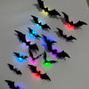 A collection of black bat wall decals illuminated by various colorful LED lights.